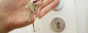 a hand holding a keychain of a house